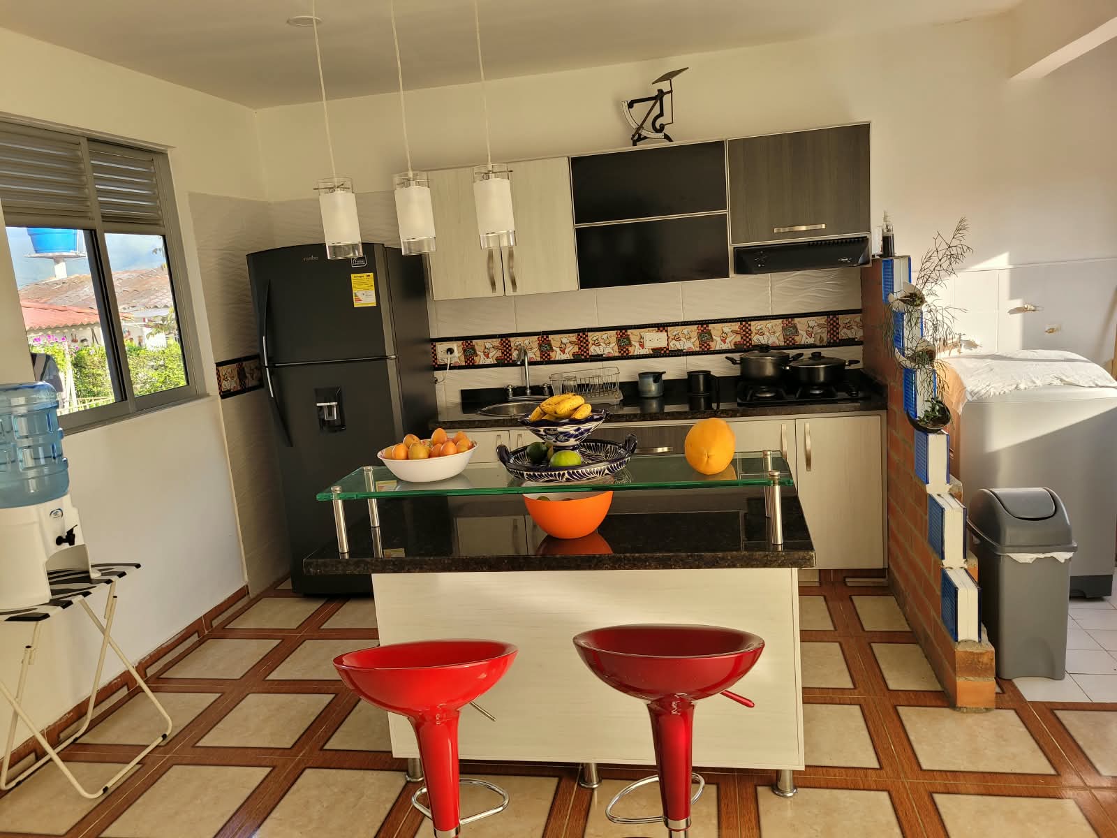 Cocina con isla y banquitos rojos